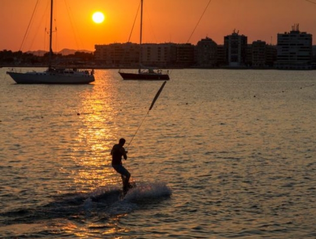 practicando wakeboard con dos barcos de fondo en un atardecer.jpg
